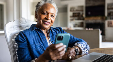 Senior woman using smartphone at kitchen table