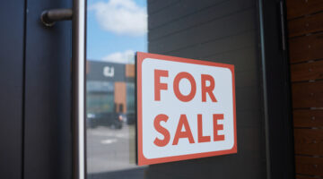 Close-up of placard For Sale hanging on the door of modern office building